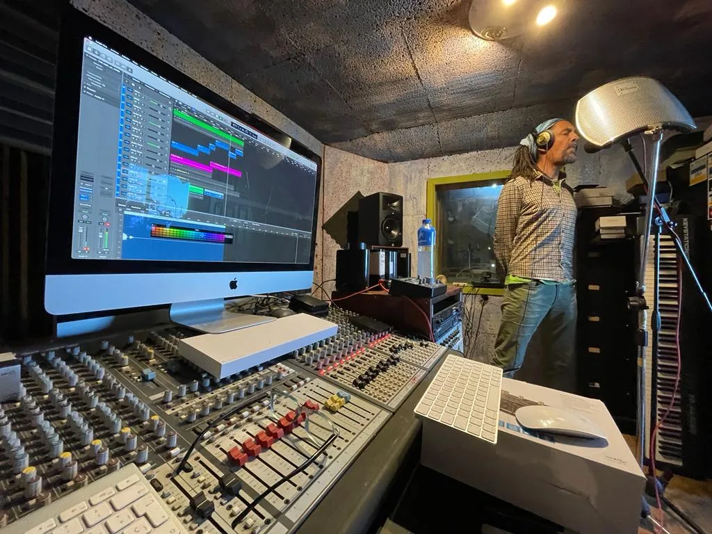 Estudio de grabación con mesa de mezclas y un cantante ante el micrófono
